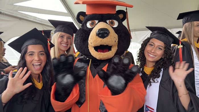 Morning ceremony graduates gather with the University mascot, Pio.